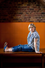 Victoria Wood. English comedian, actress, and writer, known for her sharp wit, observational humour, and memorable sketches that often captured everyday British life with warmth and intelligence. She was a multi-talented performer who also wrote and starred in television shows, plays, and musical comedies. Photographed sitting on a desk against a brick background. London. Photograph by David Levene 03 August 2010