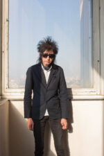 John Cooper Clarke. English performance poet, comedian, and cultural icon known for his rapid-fire delivery, sharp wit, and punk-influenced style. Emerging in the 1970s alongside the British punk movement, he brought poetry to new audiences through live performances that blended humour, social observation, and rhythmic spoken word. His distinctive look and energetic stage presence helped redefine modern performance poetry, making him one of the most recognisable poets in contemporary British culture. London. Photograph by David Levene 25 December 2012