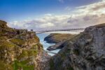Tintagel Castle in Cornwall, England — the modern pedestrian bridge was opened in 2019, reconnecting the two cliff sides where the medieval castle ruins sit. It's also famously associated with the legend of King Arthur. Cornwall. Photograph by David Levene