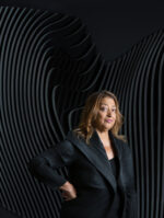 Zaha Hadid, Iraqi-British architect and the first woman to receive the Pritzker Architecture Prize, photographed against a sculptural curved relief surface echoing the fluid forms characteristic of her architectural vision, London. Photograph by David Levene, 19 September 2013.