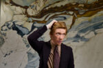 Domhnall Gleeson, Irish actor, portrait in dark suit and tie with hand in hair against abstract marble artwork background. London. Photograph by David Levene, 20 August 2026